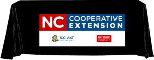 A black table cover illustration displaying the N.C. Cooperative Extension logo.